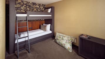 A bunk bed with a ladder, a wooden headboard, a bedside table, and a patterned pillow.