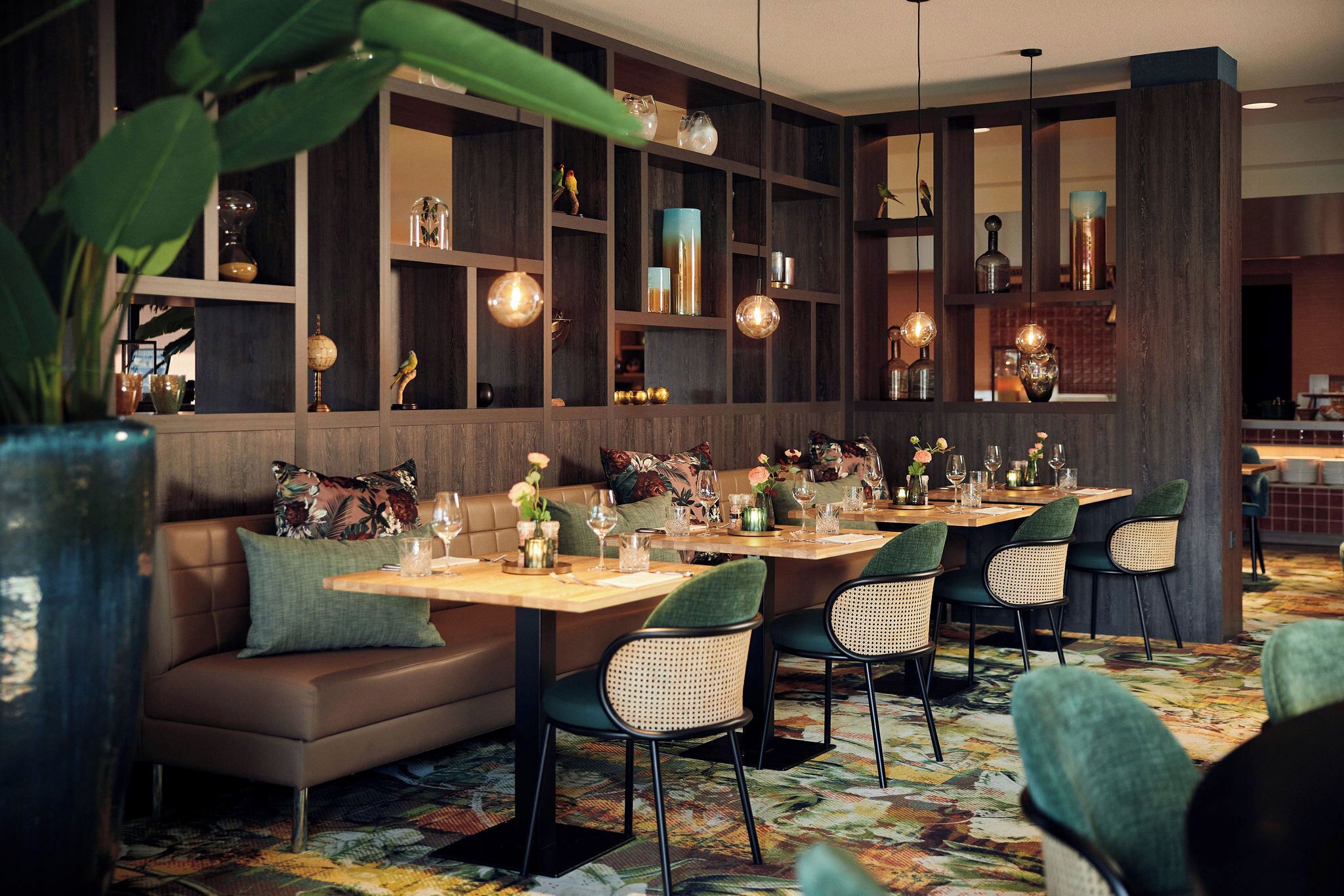 Een restaurant met een lange tafel, comfortabele zitplaatsen en decoratieve schappen.