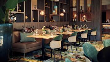 Een restaurant met een lange tafel, comfortabele zitplaatsen en decoratieve schappen.