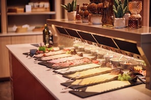 A buffet table with various food items and utensils.