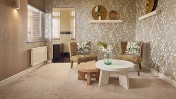 Een kamer met een ronde tafel, twee stoelen, een radiator en een raam.