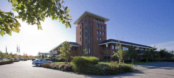 A multi-story building with a parking lot and landscaped areas.