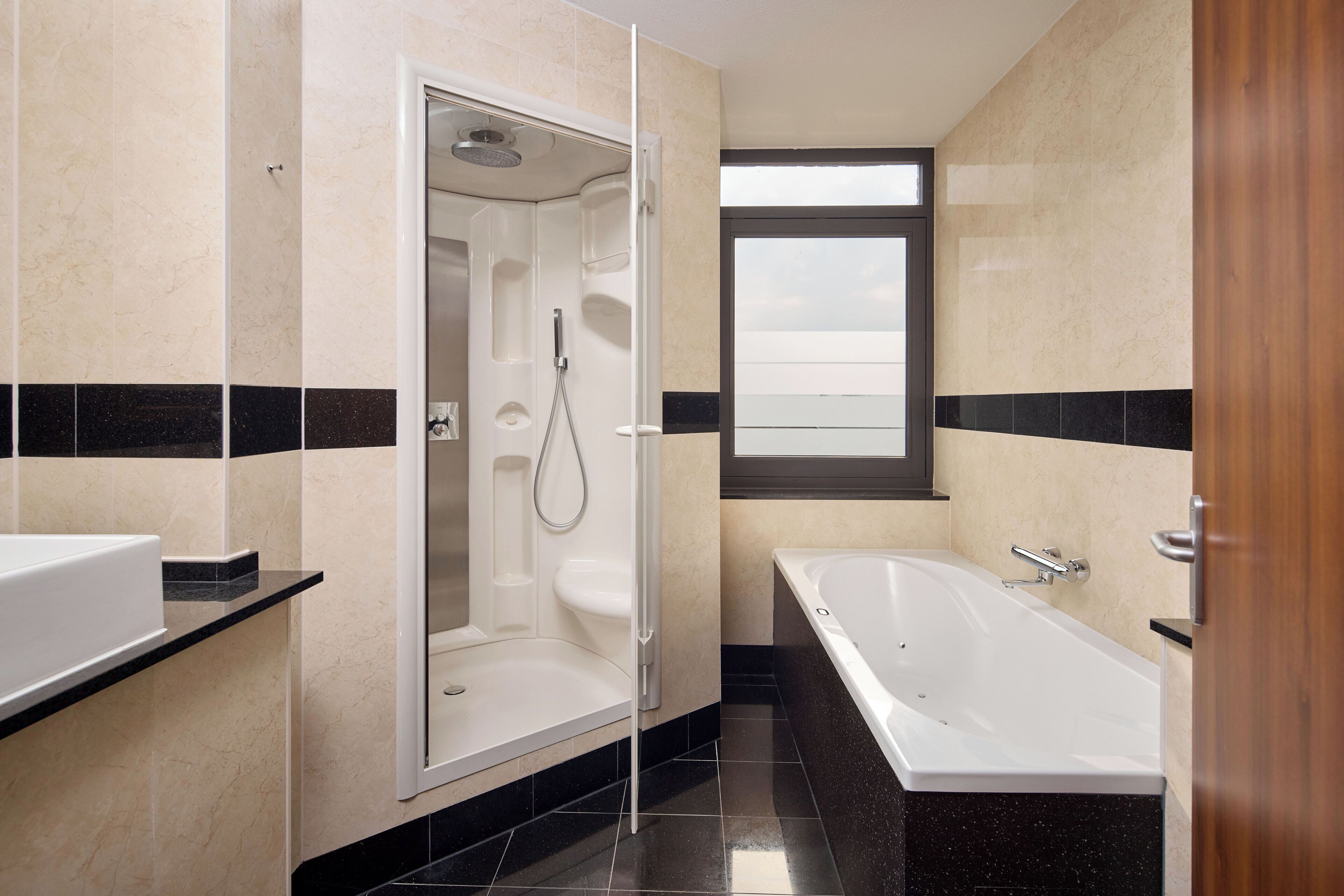 Un baño moderno con ducha, bañera y ventana que proporciona luz natural.