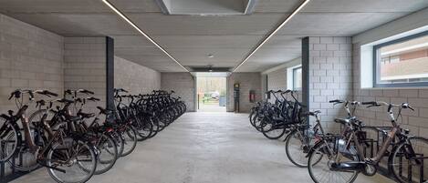 A bike rental station with rows of bicycles, concrete walls, and a long corridor.
