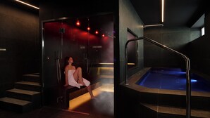 A spa area with a hot tub, a woman sitting on a bench, and a staircase leading to a steam room. - Hotel Romagna (Cattolica)