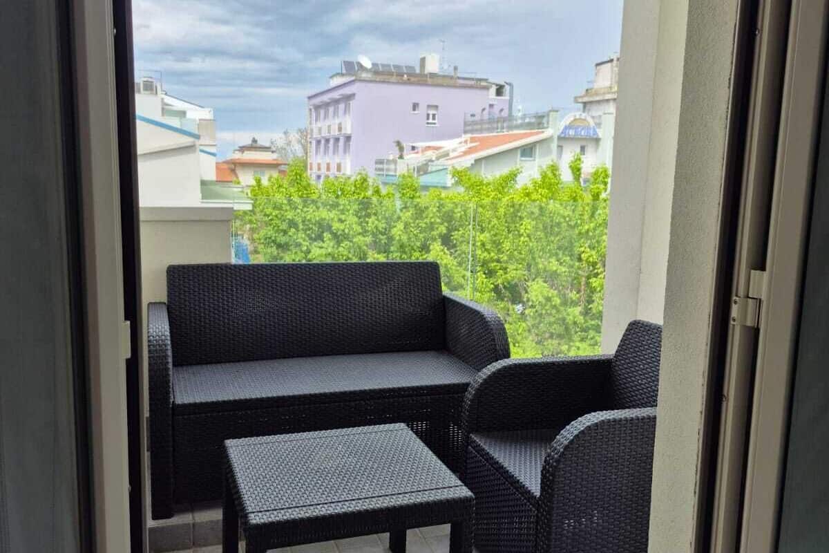 Un balcón con un sofá de mimbre negro, una mesita y una silla.