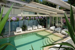 Una piscina techada, una piscina al aire libre de temporada, sombrillas