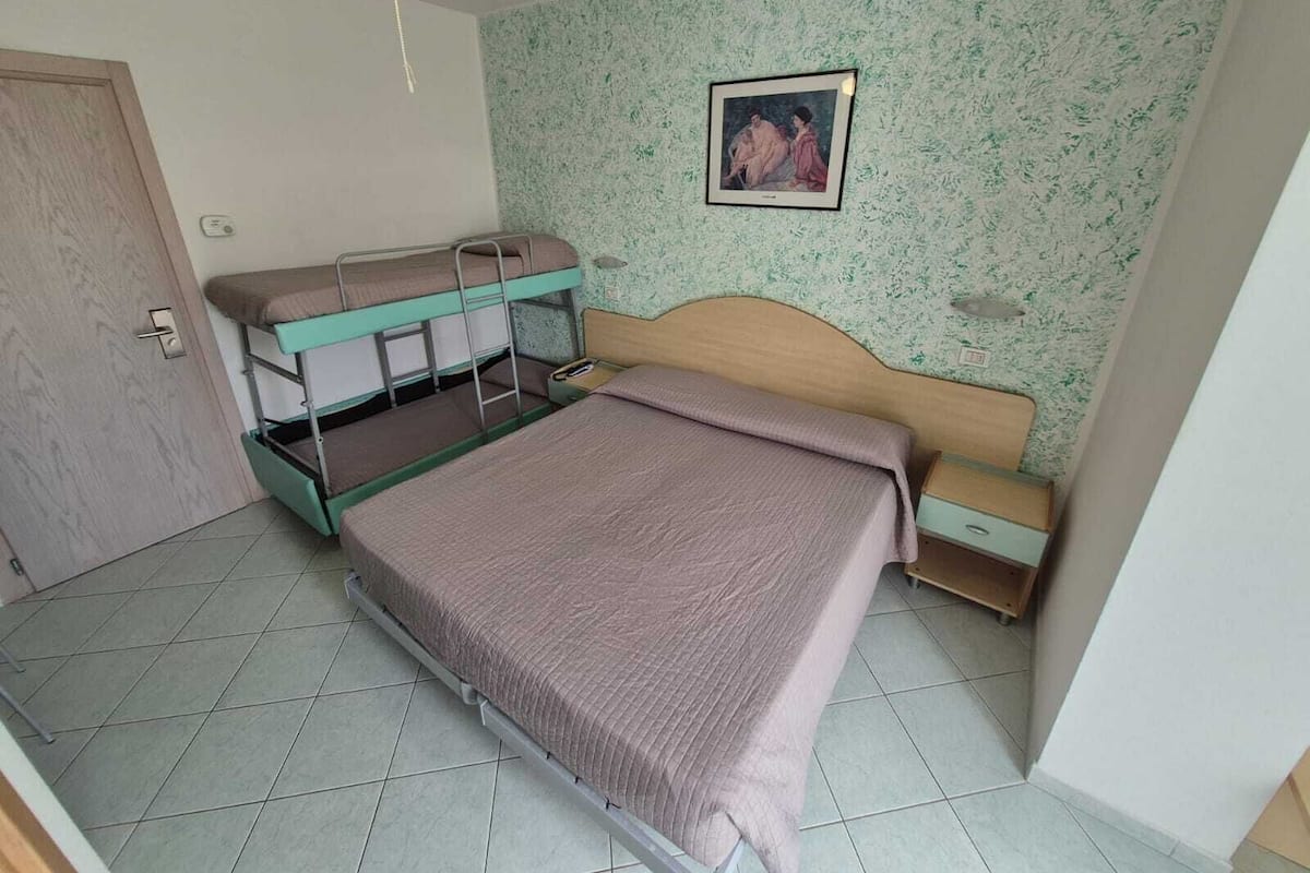Una habitación con literas, un cabecero de madera, un cuadro en la pared y una puerta.