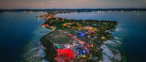 A large island with a central building illuminated in red, surrounded by water and a moonlit sky.