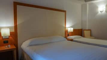 Ein Hotelzimmer mit zwei Einzelbetten, Holz-Kopfteilen und Nachttischlampen.