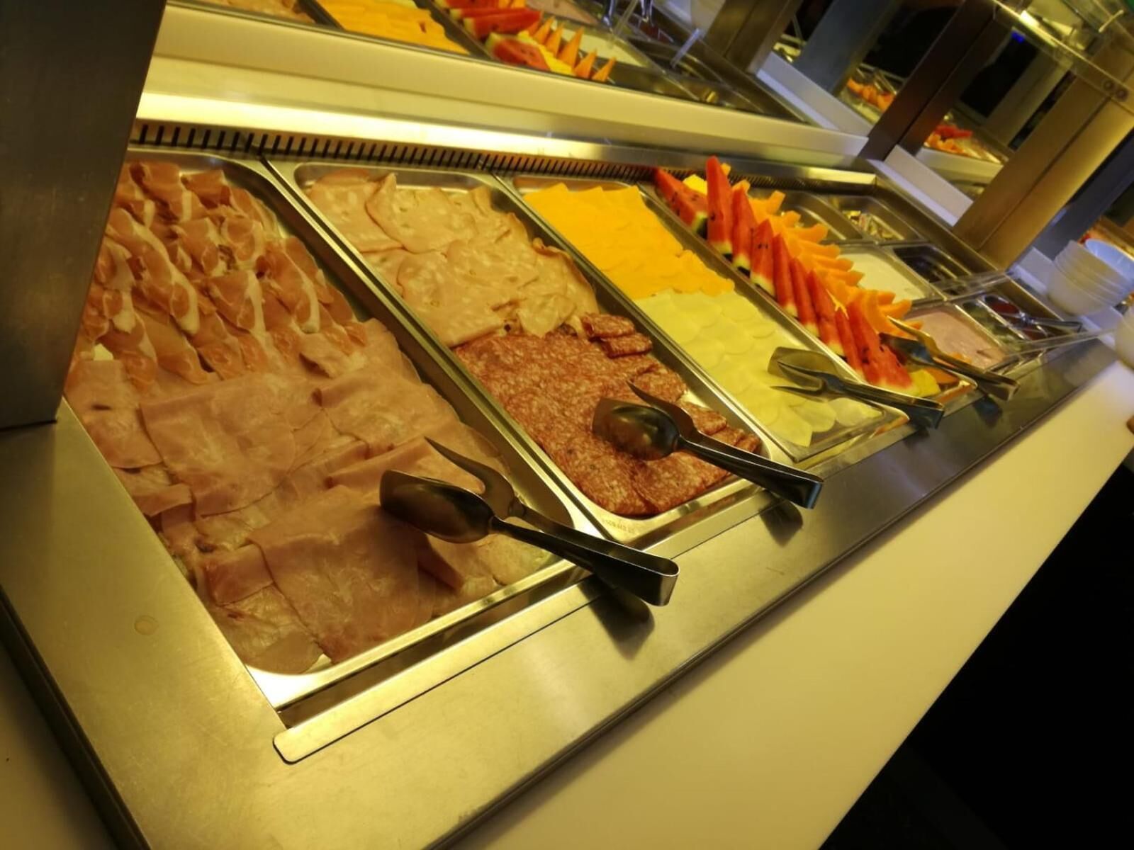 A buffet with various food options including meats, cheeses, and fruits.
