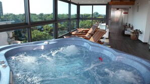 Un jacuzzi con vistas a la ciudad, sillas de madera en la terraza y un diseño interior moderno.