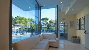 Un vestíbulo de hotel moderno con un amplio ventanal que da a una zona de piscina.
