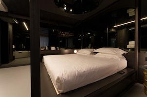 Un dormitorio moderno con una cama grande, una mesita de noche, un espejo y un banco empotrado.