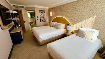 A hotel room with two beds, a built-in desk, and a wardrobe.
