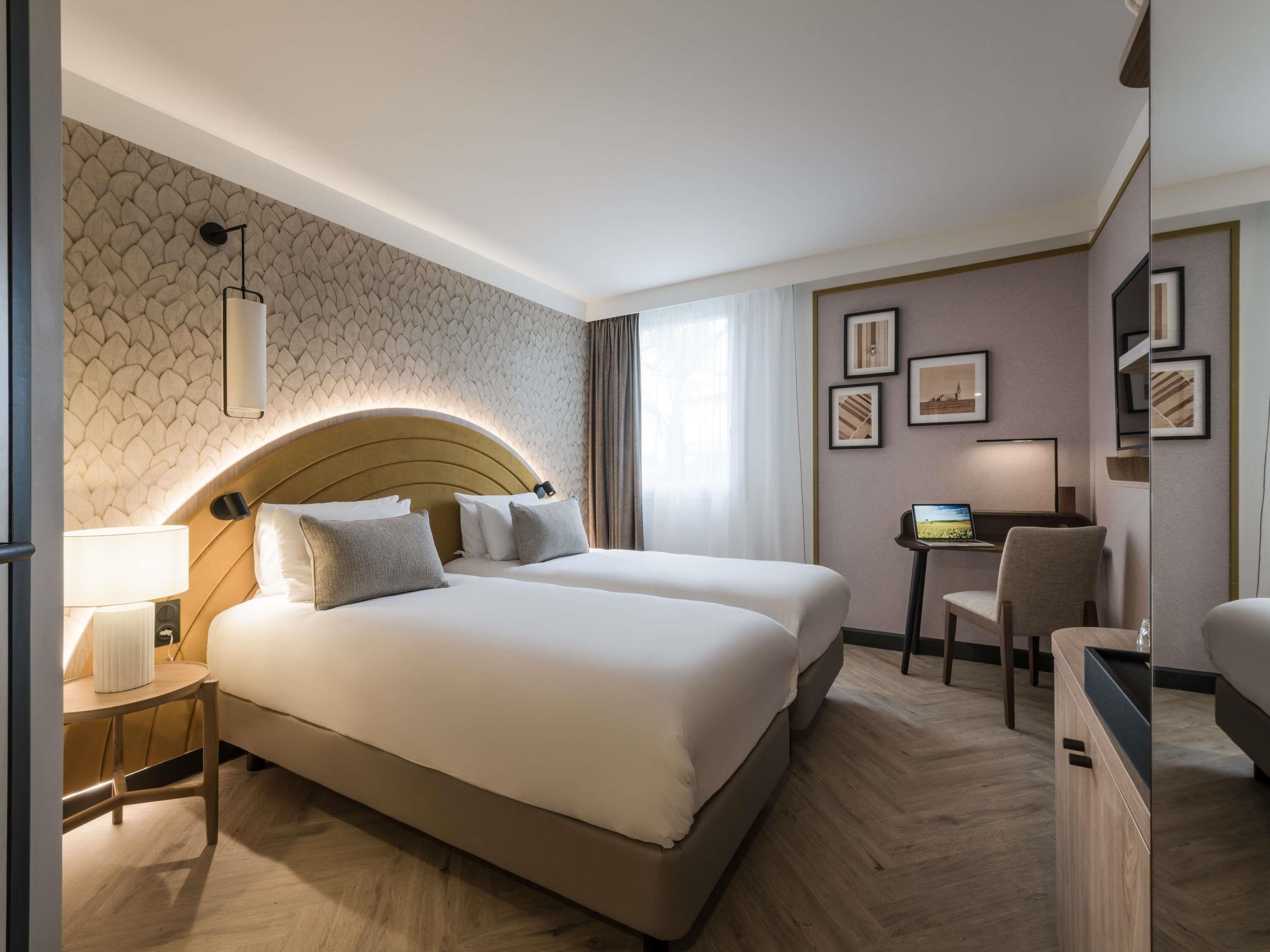 A hotel room with a large bed, bedside tables, a desk, and a chair.