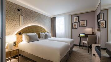 A hotel room with a large bed, bedside tables, a desk, and a chair.