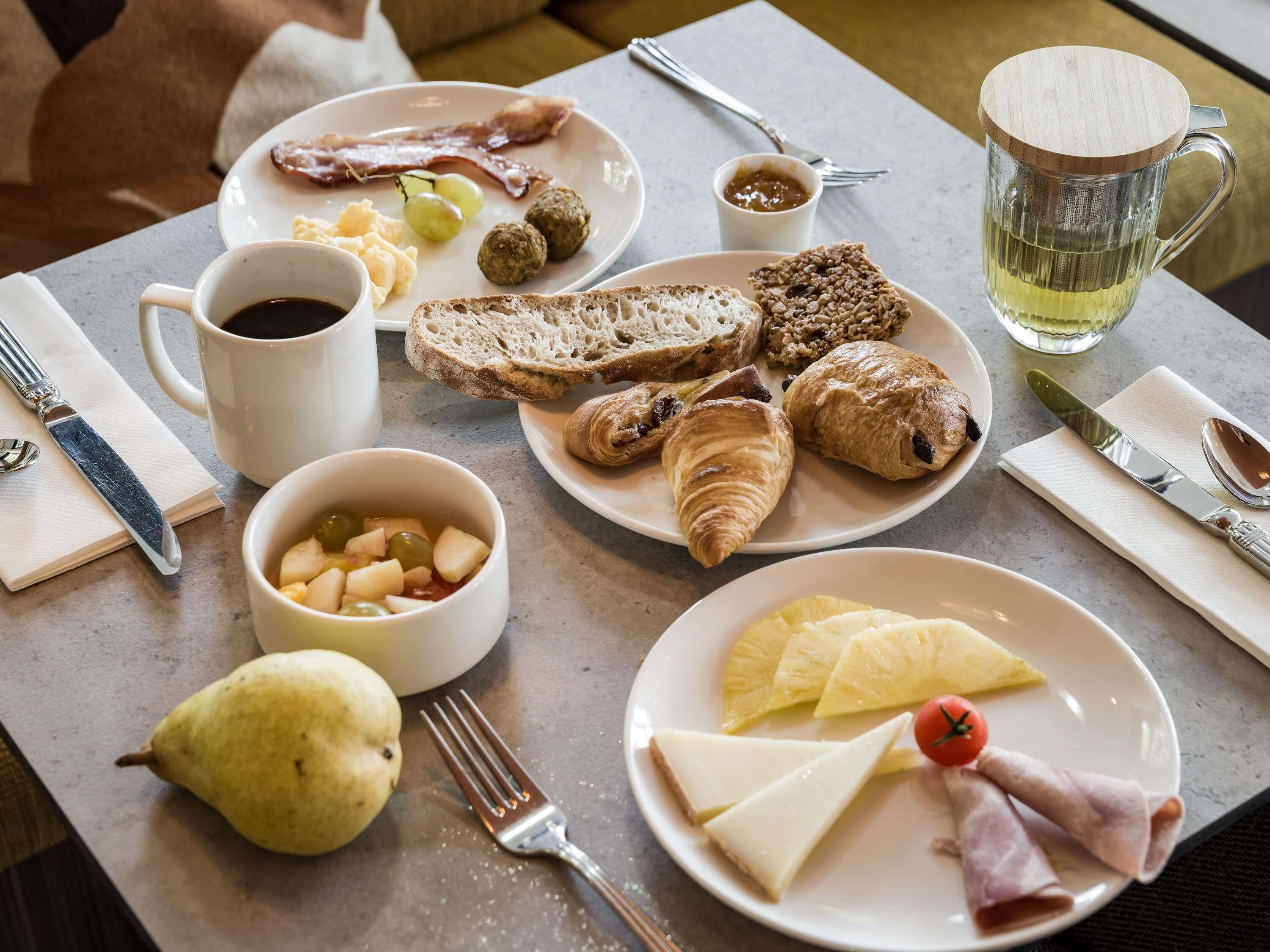 Desayuno con platos de comida, una taza de café, un vaso de té y cubiertos.
