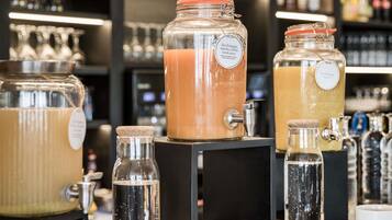 A beverage station with multiple dispensers and containers, including a large orange-colored drink and smaller bottles.