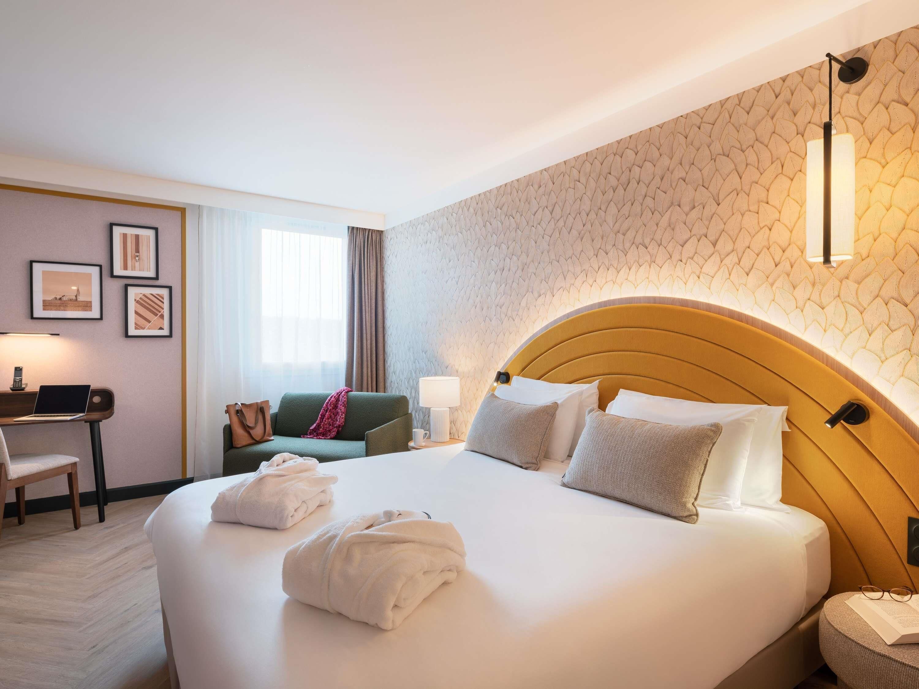 Une chambre d’hôtel avec un grand lit, un bureau avec un ordinateur portable, une chaise et un canapé.