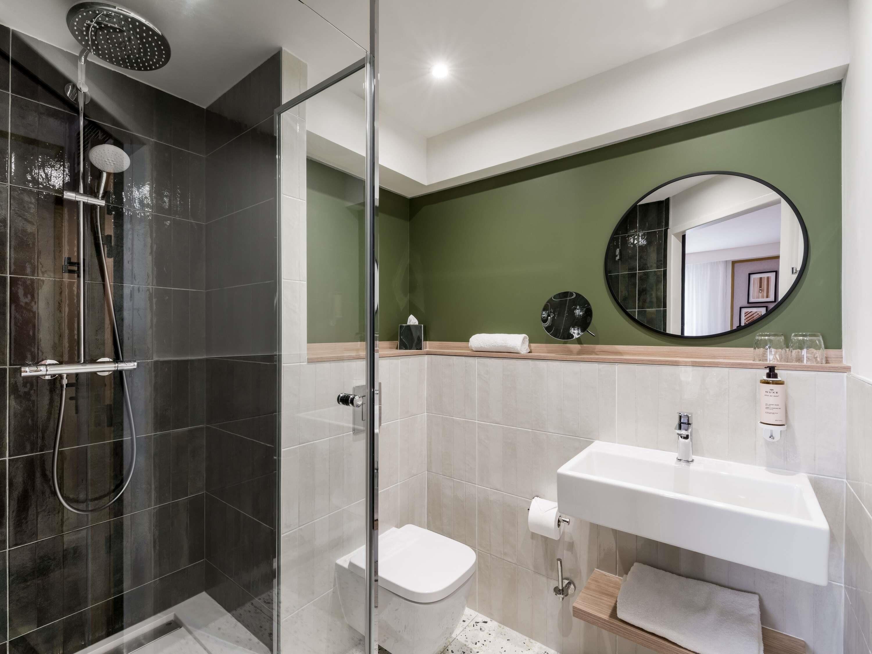 Un baño moderno con ducha de vidrio, inodoro y lavamanos con espejo.