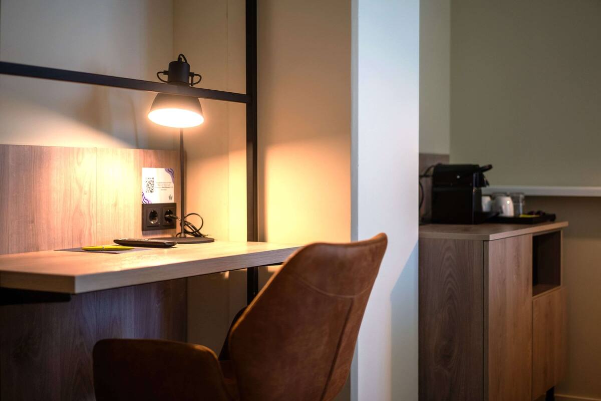 Una cucina con un piano di lavoro in legno, una sedia, una lampada e una macchina per il caffè.