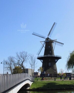 Stroll across the pedestrian bridge to the historic windmill, situated near a serene body of water.