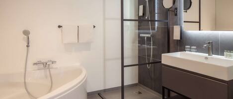 Un baño moderno con una bañera independiente, cabina de ducha con mampara de vidrio y tocador con espejo.