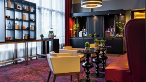 A modern hotel lobby with a bar area, seating, and decorative shelves.