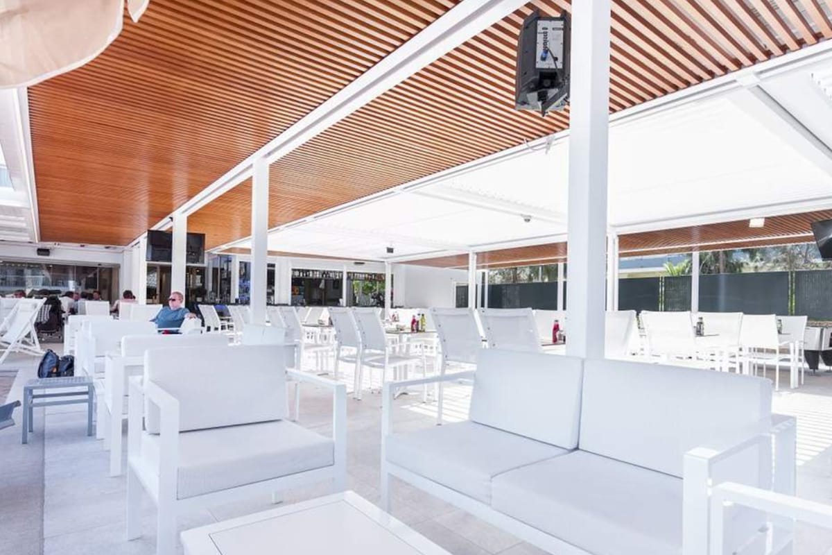 Un espace extérieur aménagé avec du mobilier blanc et un plafond en bois.