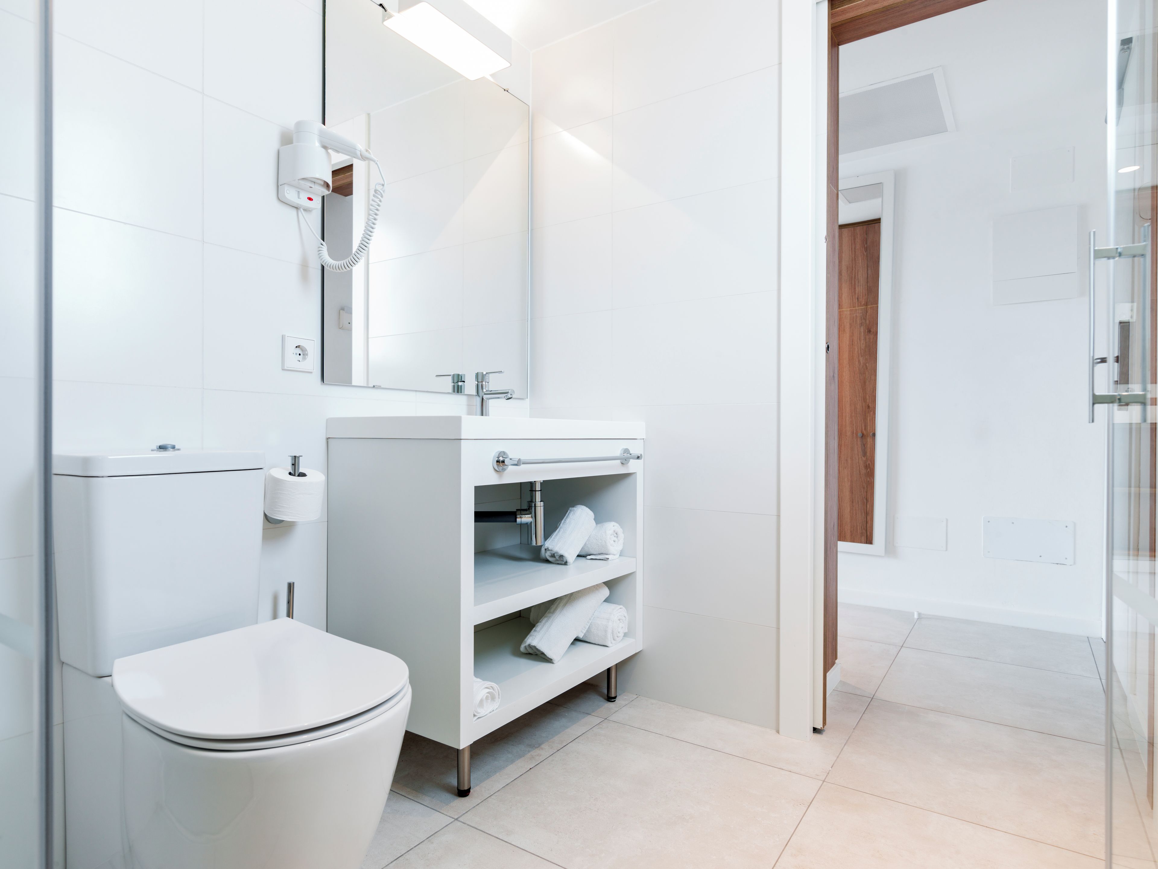 A modern bathroom with a toilet, sink, and mirror.