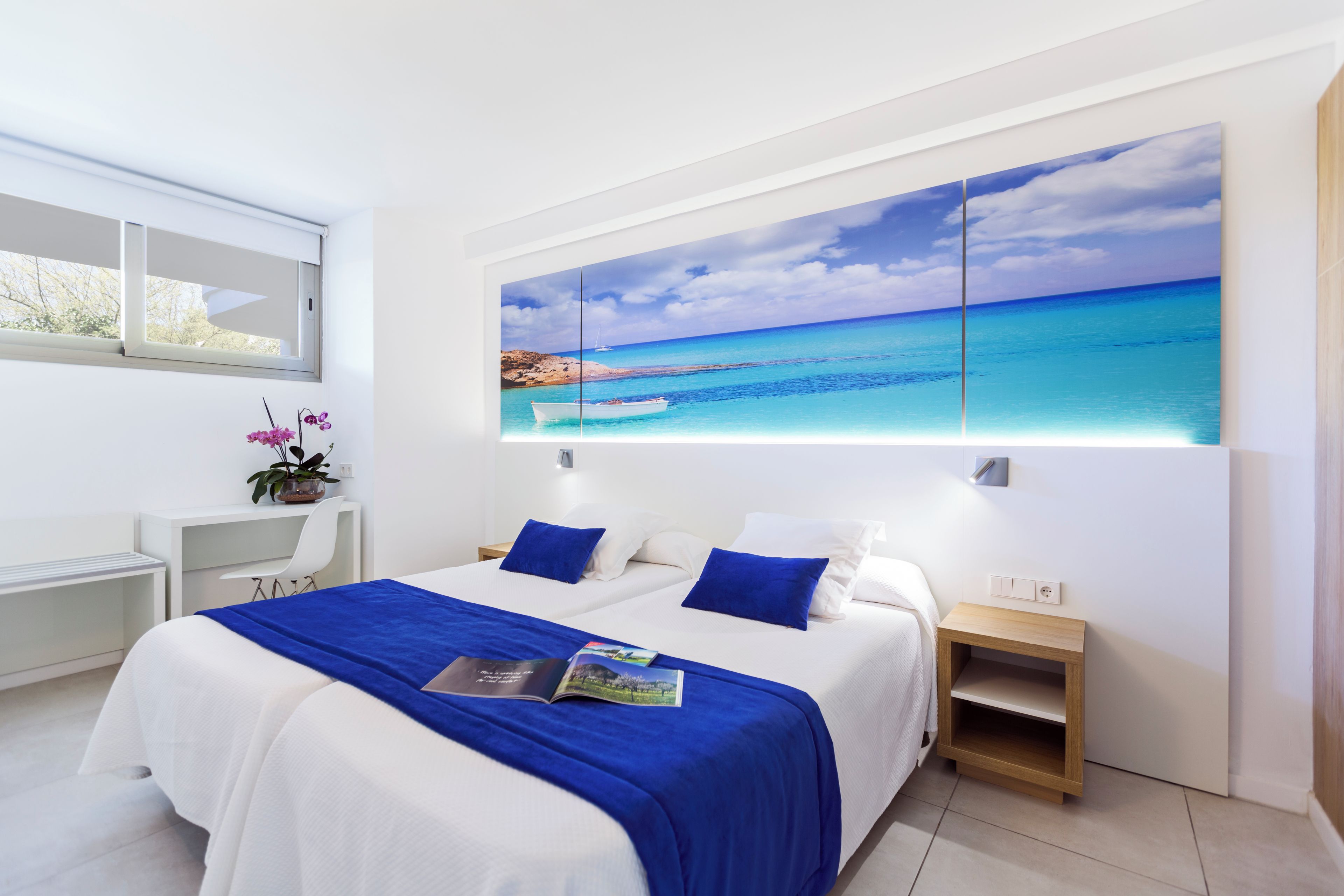 Una habitación de hotel moderna con una cama grande, un escritorio y vista al océano.