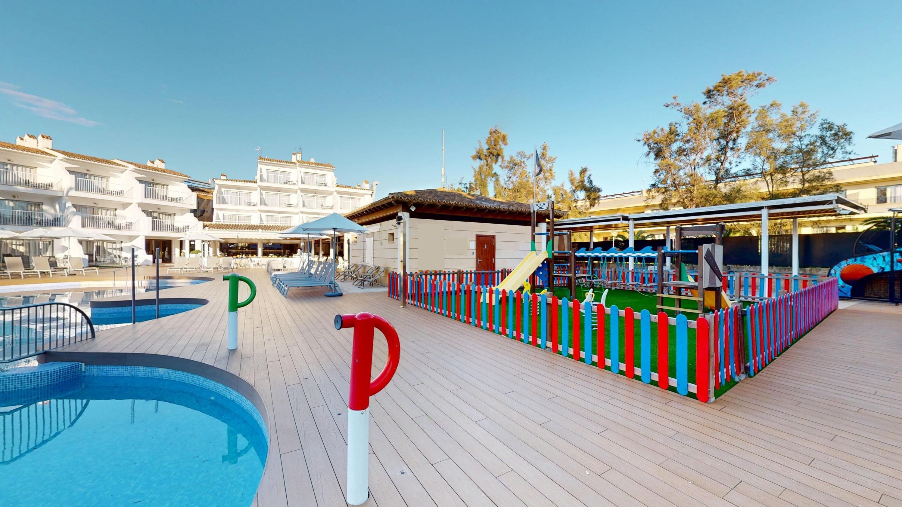 Un pont de navire de croisière équipé d’une piscine, de chaises longues, d’un espace de jeux pour enfants et d’un bâtiment doté de nombreux balcons.