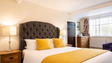 A bedroom with a large bed, two bedside tables, a dresser, and a window with curtains.