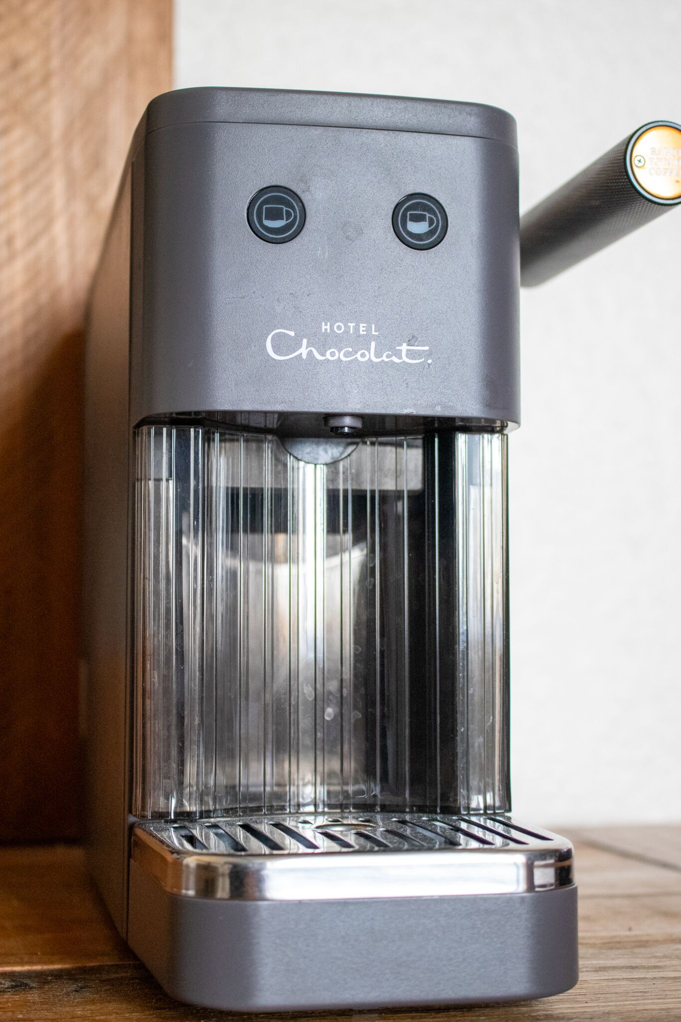 Een hotel espressomachine van chocolademerk met een transparante glazen voorzijde en een metalen basis.