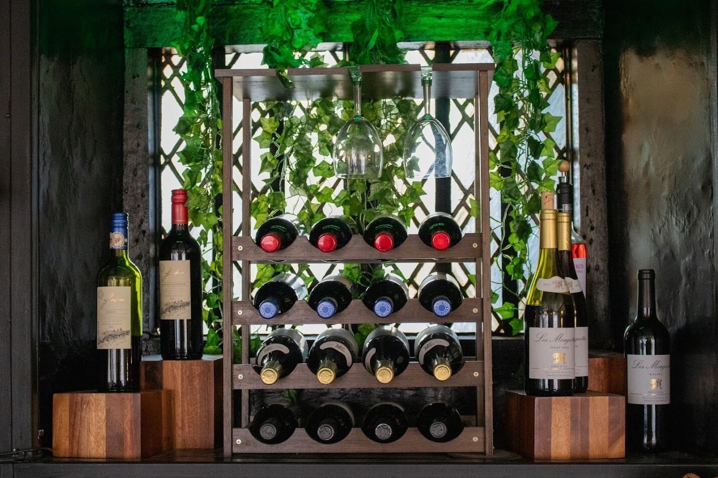 A wine rack with bottles, surrounded by greenery.