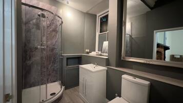 Une salle de bain moderne avec une douche à parois de verre, un lavabo blanc et des toilettes.