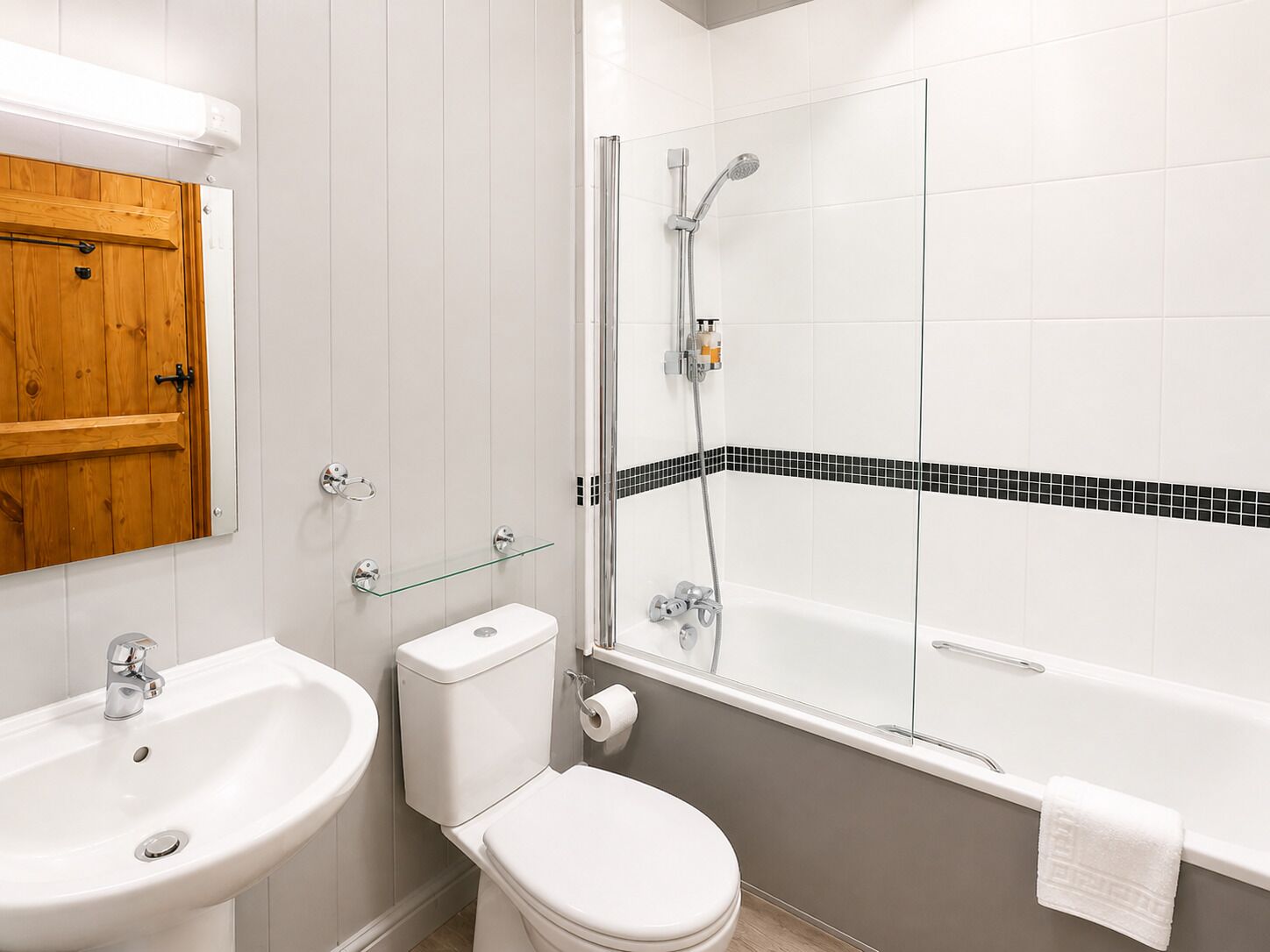 Et badeværelse med vask, toilet og badekar.