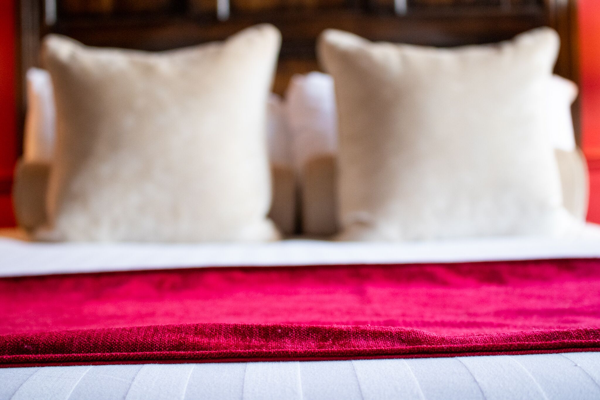 A bed with a red blanket and two pillows.