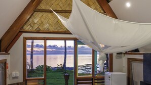 Un dormitorio con una cama grande, vista al mar y un ventilador de techo.