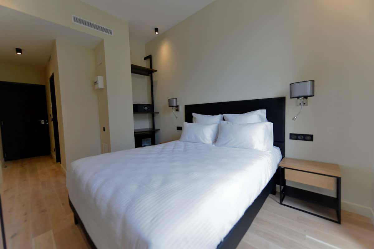 Ein modernes Hotelzimmer mit einem großen Bett, Nachttischen und Wandleuchten.