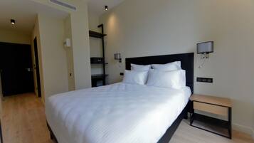 A modern hotel room with a large bed, bedside tables, and wall-mounted lamps.
