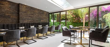 Een modern interieur met een stenen muur, een zwarte bank en een tafel met stoelen.