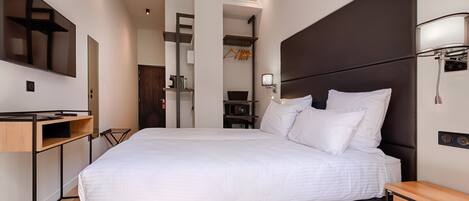 Una habitación de hotel moderna con una cama grande, un escritorio y un televisor.