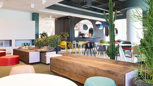 A modern indoor space with a wooden table, colorful chairs, and potted plants. - Garda Hotel (Montichiari)