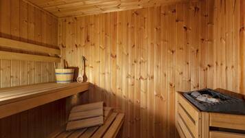 Eine Holzsauna mit Bänken, einem Holz-Eimer und einem Schöpflöffel.