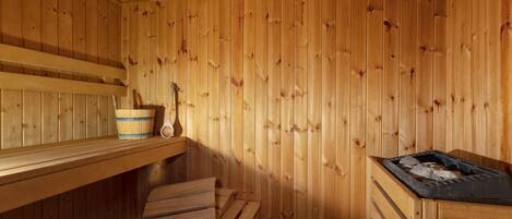 A wooden sauna with benches, a wooden bucket, and a ladle.
