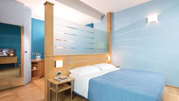Un dormitorio moderno con cama, mesita de noche y un pequeño escritorio con silla.
