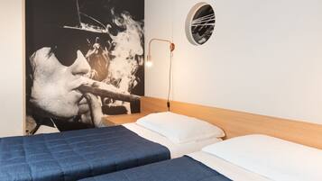 Ein Hotelzimmer mit einem Bett, einem an der Wand befestigten Spiegel und einem Poster, das eine Person beim Zigarrenrauchen zeigt.