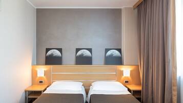 Habitación de hotel con dos camas, cabecera de madera y tres láminas decorativas con las fases de la luna.